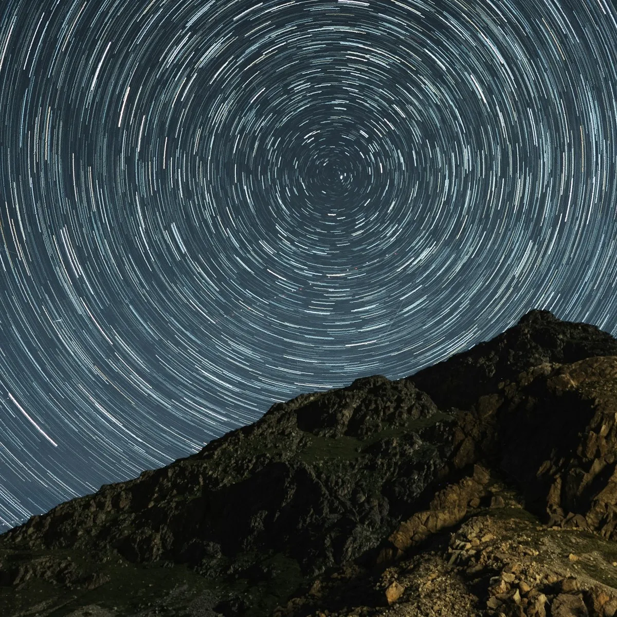 長曝光下環繞天極的同心星軌與山稜剪影，象徵靈魂編碼中反覆上演的人生軌跡